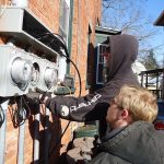 Electricians installing meter panels on a house