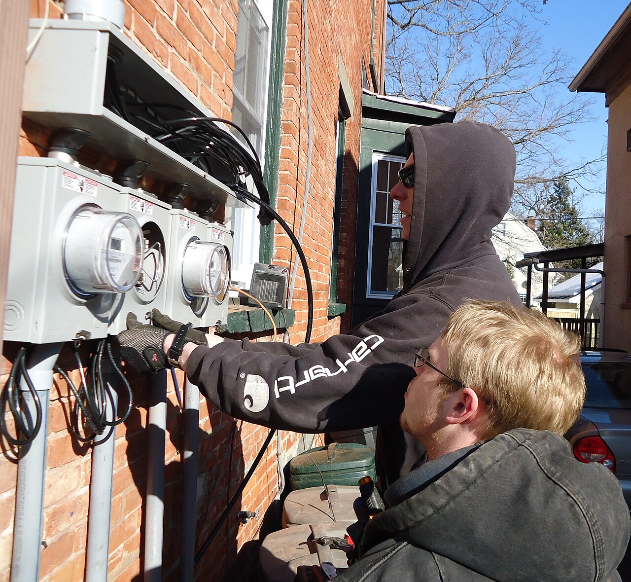 Electricians installing meter panels on a house