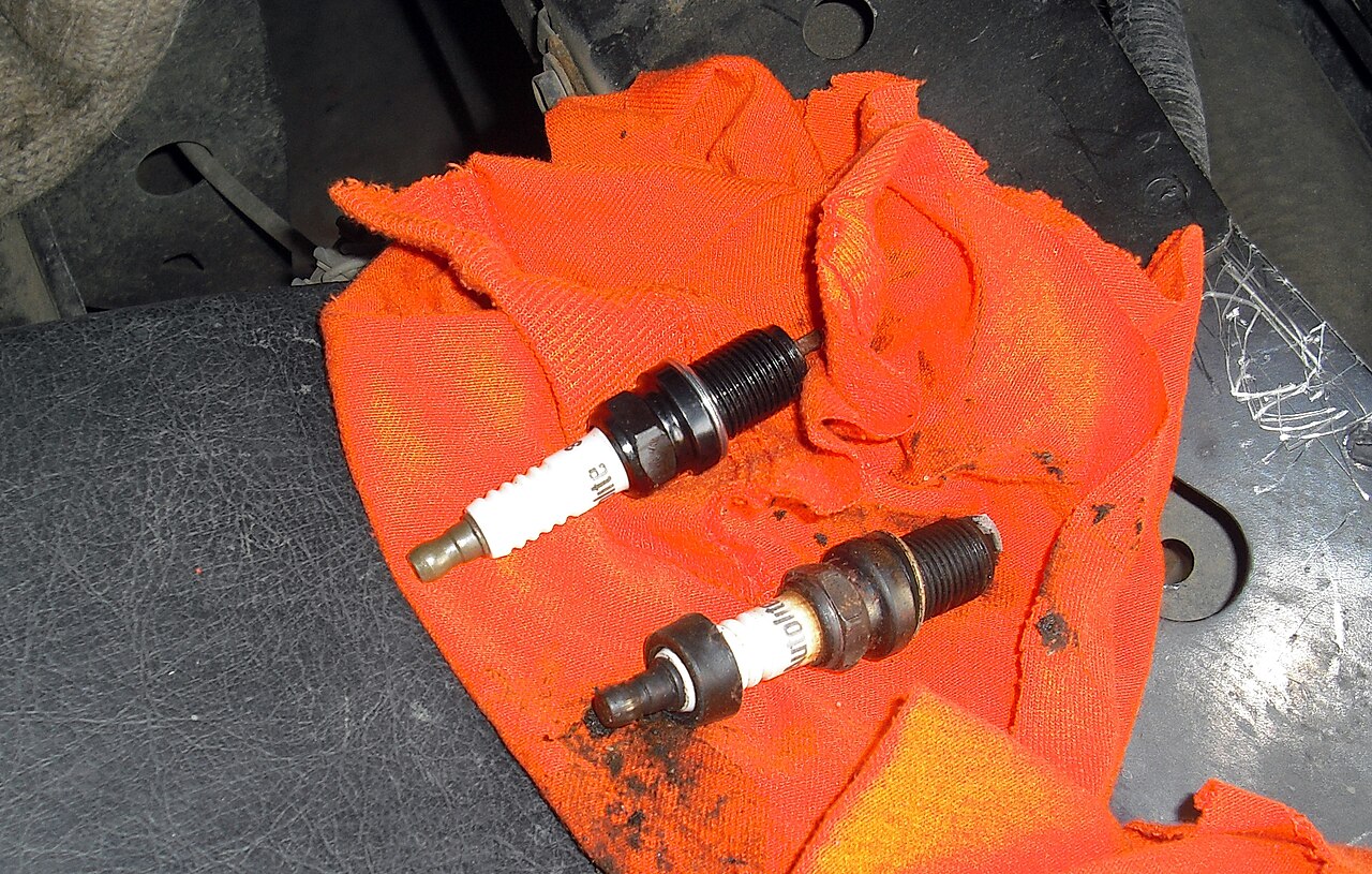 Old spark plug next to a new replacement spark plug