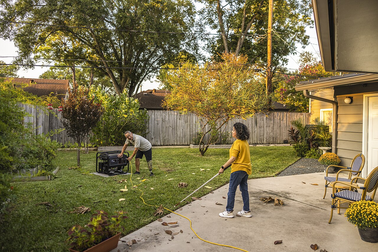 Two people setting up a portable generator safely outdoors